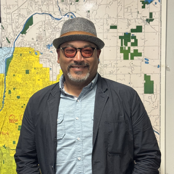 Staff photo of Alex, Alex standing in front of Grand Rapids Map